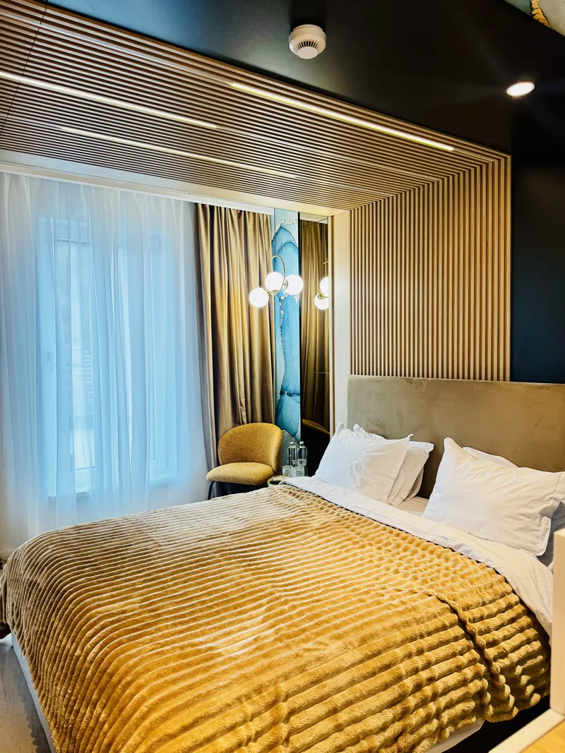 King-size bed beside a curtained window, a wall of blue-toned natural stone and golden accents, Family Room MAPAMONT Văliug