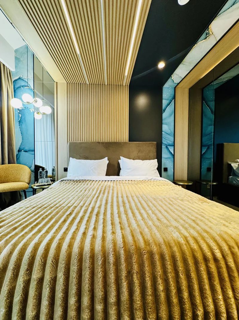 King-size bed on the main level, with wood paneling and a wall of blue-toned natural stone, Family Room MAPAMONT Văliug