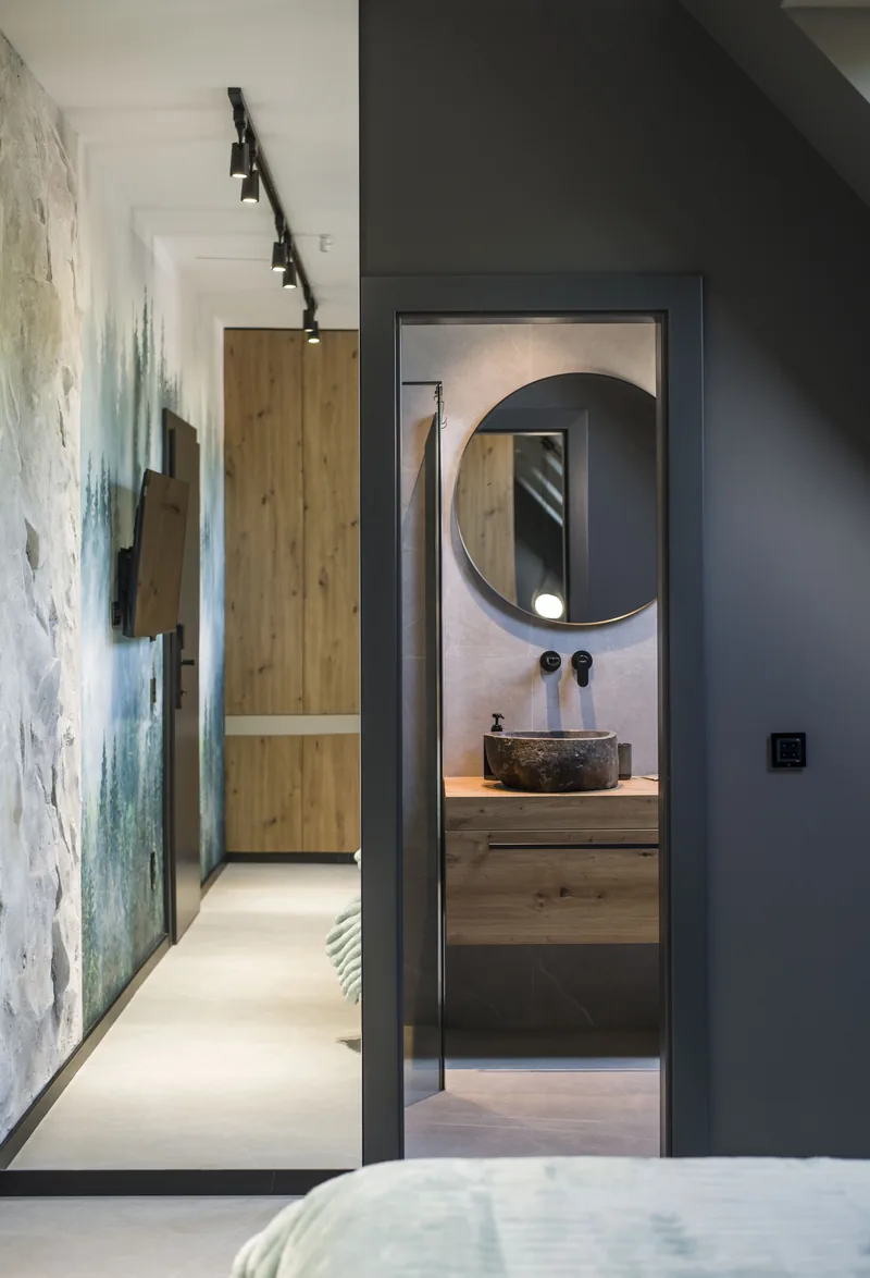 The en-suite bathroom seen through the door, with stone washbasin and round mirror, Standard Loft Room MAPAMONT Văliug