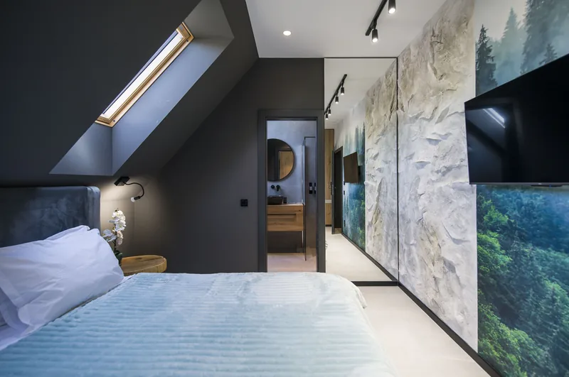 Bed under the Velux skylight, with stone wall and large mirror, Standard Loft Room MAPAMONT Văliug