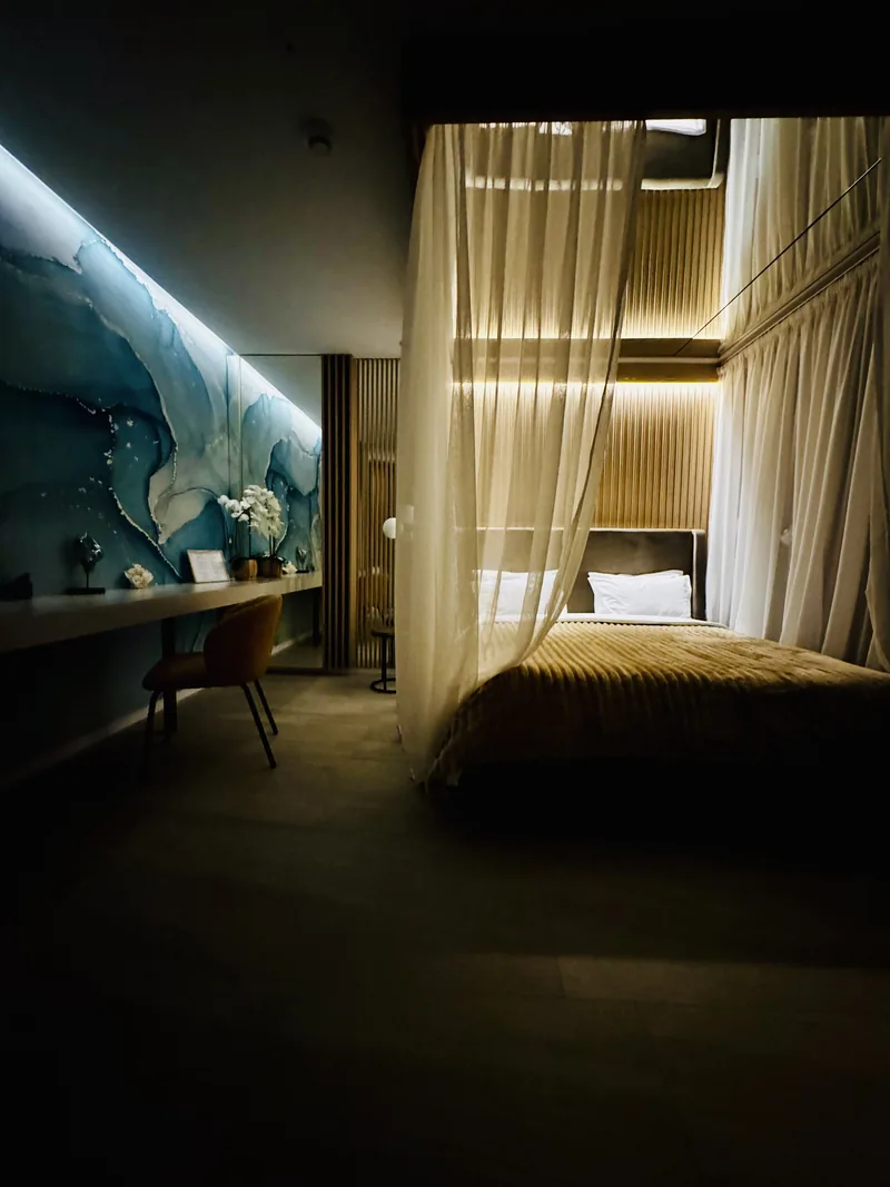 Romantic atmosphere with canopy bed and an illuminated wall of blue-toned natural stone, VIP Room MAPAMONT Văliug