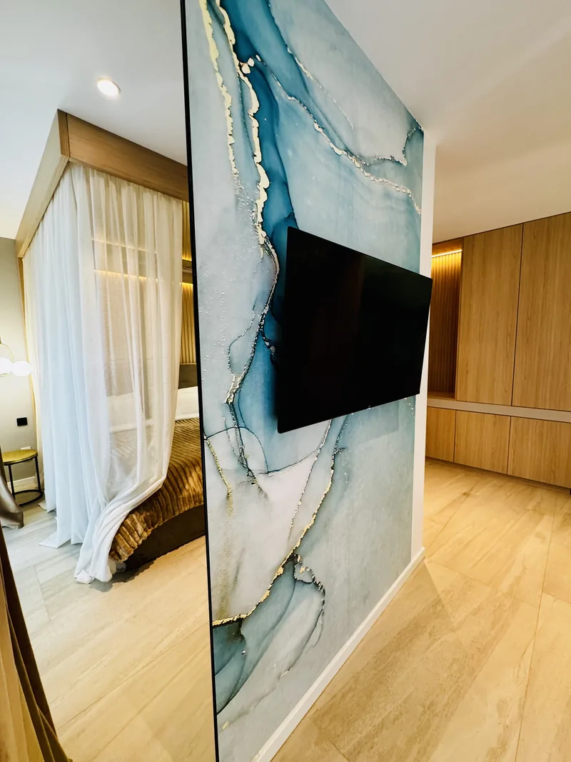 Wall of blue-toned natural stone with TV and a large mirror reflecting the bed, VIP Room MAPAMONT Văliug